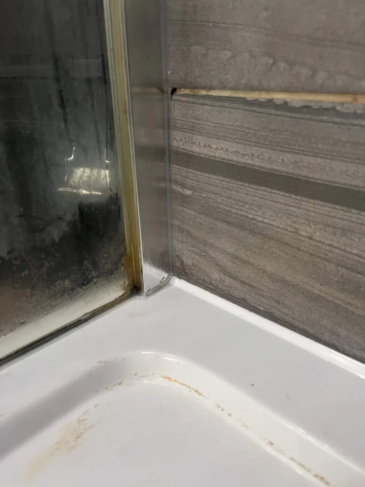Shower corner after mould removal and resealing, clean silicone line