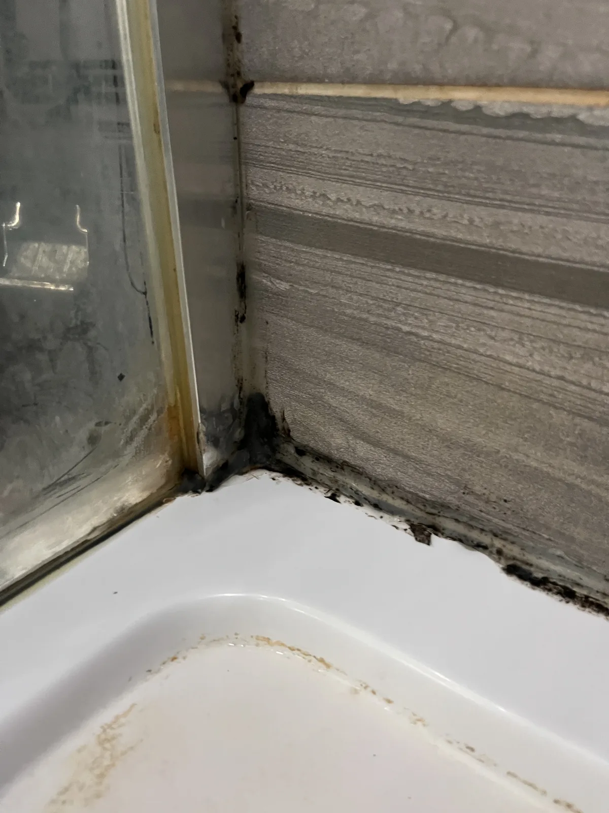 Shower corner before resealing, mouldy blown silicone