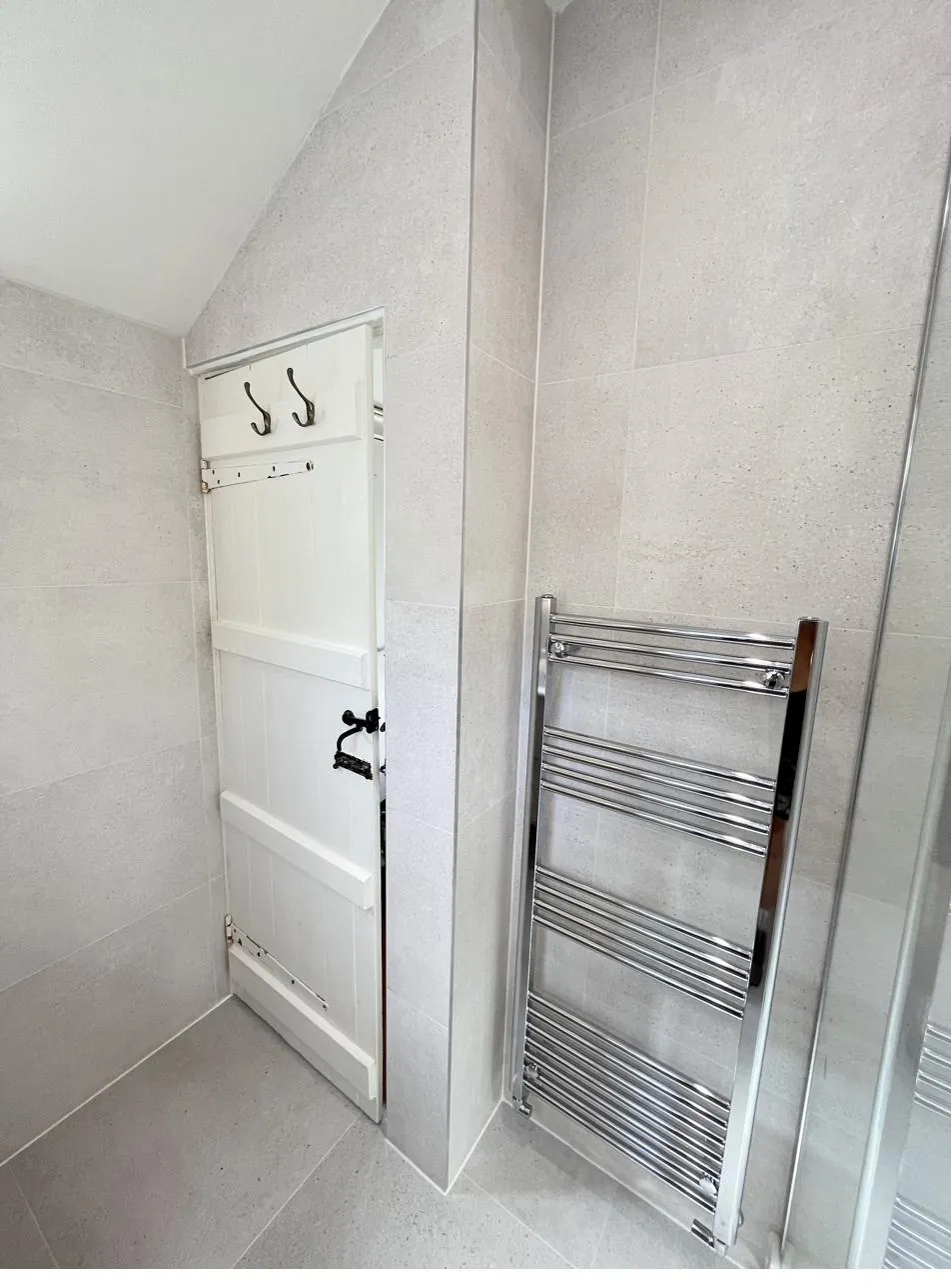 Bathroom radiator pipework sealed neatly against tiled wall