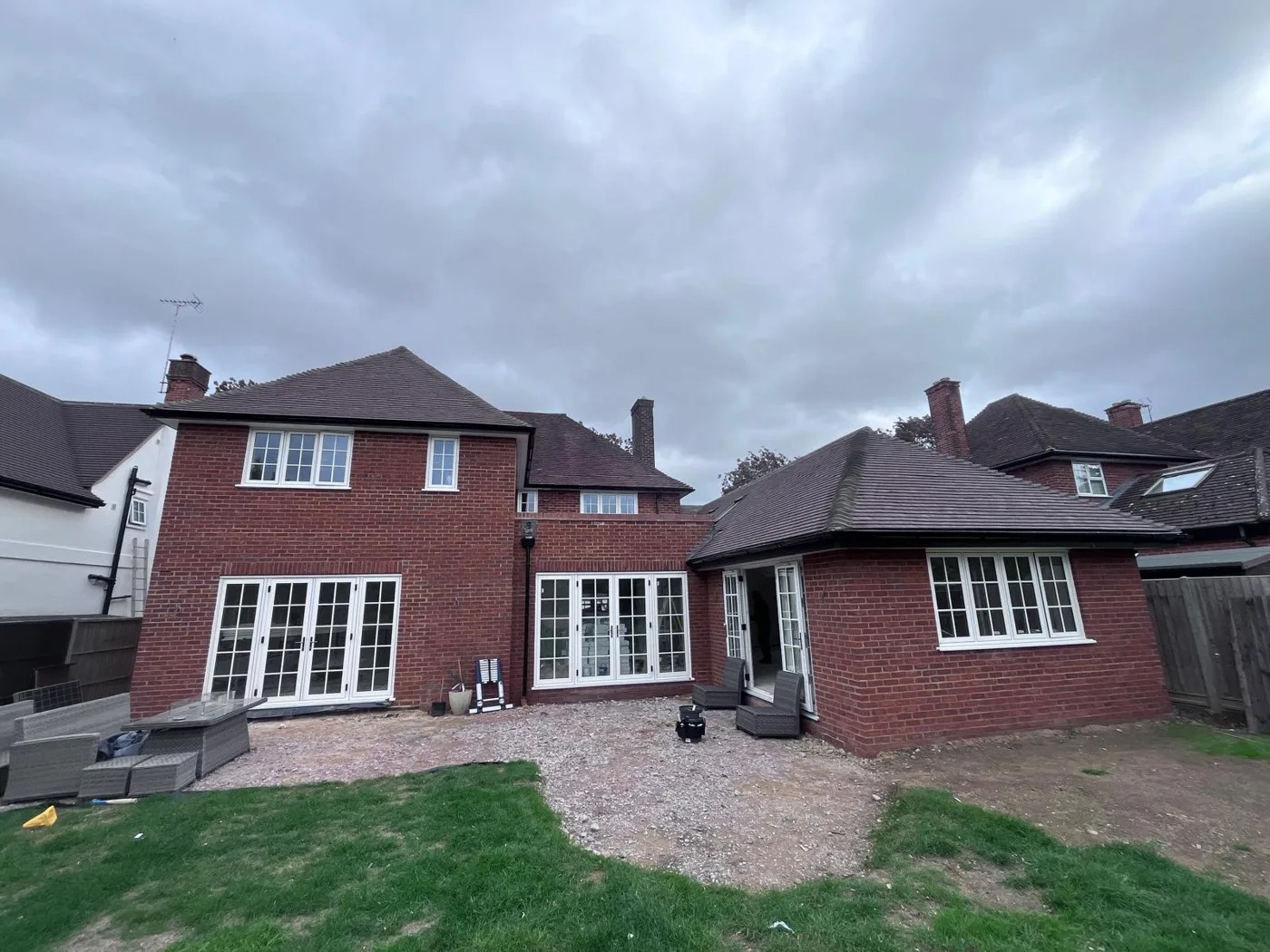 Rear of a red brick house and extension with white French doors and windows, sealed and finished