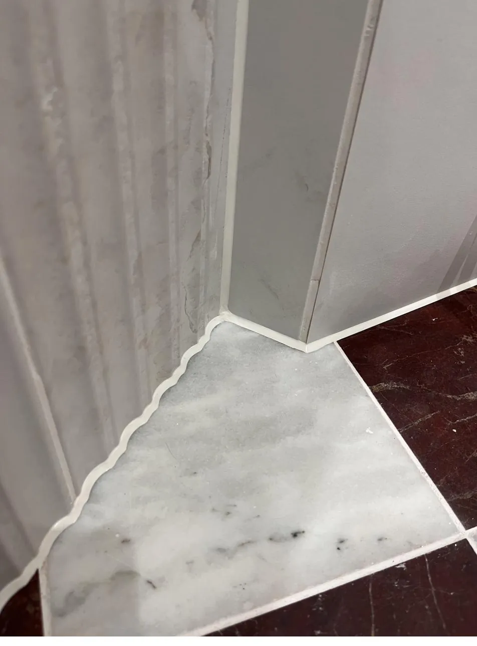 Flush sealant line where fluted tile meets marble floor