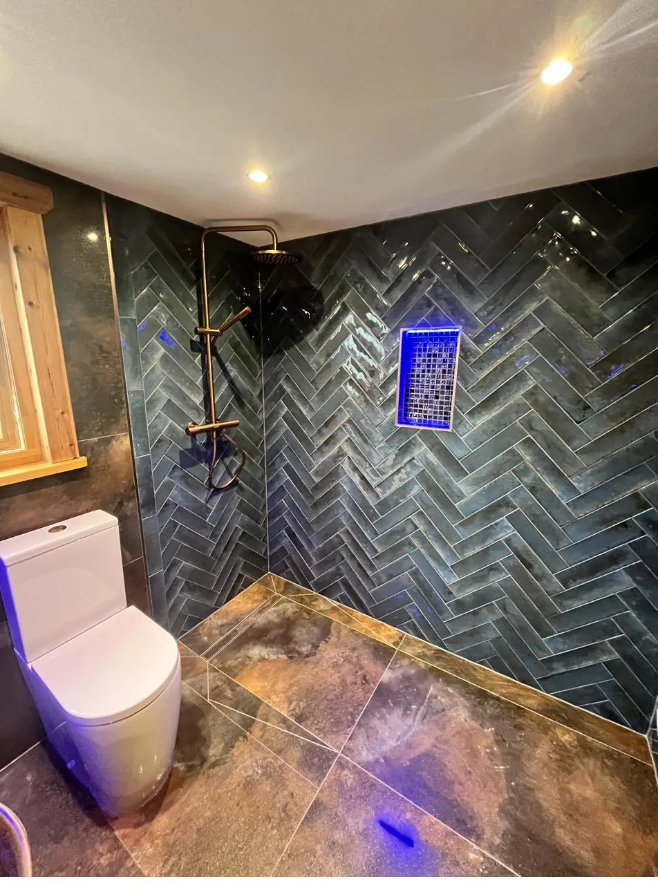 Dark slate herringbone shower with neon LED niche
