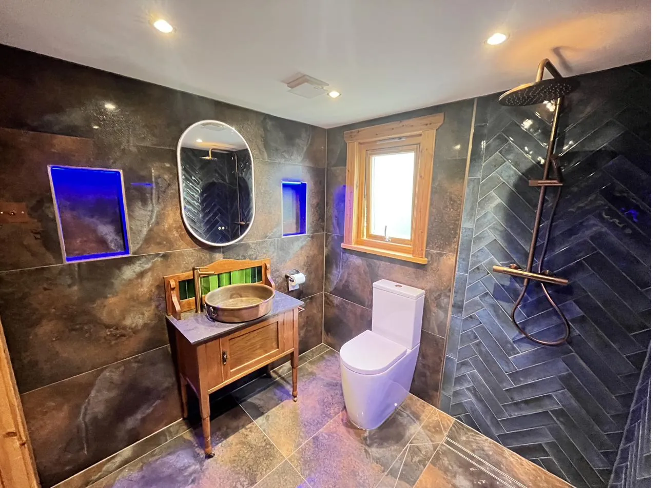 Dark slate herringbone shower with neon blue LED niche lighting