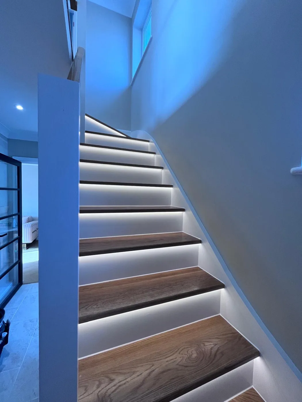 Oak staircase with LED-lit white risers and neatly sealed edges